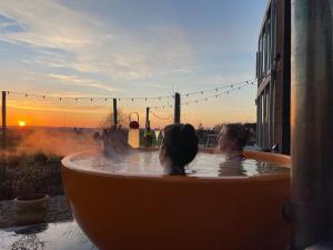 - une baignoire avec vue sur le coucher du soleil dans l'établissement Huis van Hout - architectenwoning met grote panorama tuin - design hot tub optioneel, à Herk-de-Stad