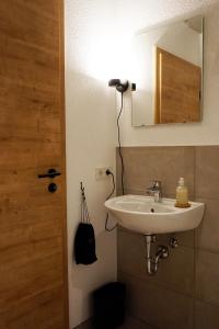La salle de bains est pourvue d'un lavabo et d'un miroir. dans l'établissement Talbach Apartments, à Buchen