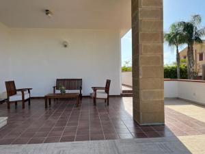 een patio met 2 stoelen en een tafel op een tegelvloer bij Villa Capri Holiday Home in Campofelice di Roccella