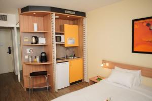 sypialnia z łóżkiem oraz kuchnia z kuchenką mikrofalową w obiekcie 5 minutes du Zénith - Studio Chic w mieście Pantin