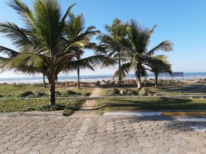 a cobblestone road next to a beach with palm trees at Hostel Mazoca in Peruíbe