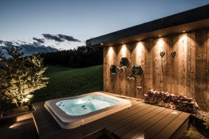 una bañera de hidromasaje en la parte superior de una terraza de madera en Alpin Boutique Villa Gabriela - Adults Only, en Castelrotto
