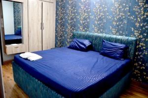 een slaapkamer met een blauw bed met blauwe lakens en een spiegel bij Pinakin Homestay in Ujjain