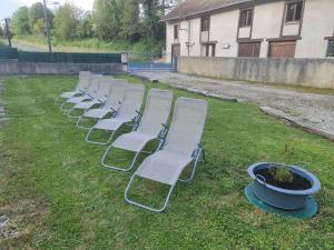 a row of white chairs sitting in the grass at Au Pilandre in Arinthod