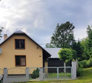 ein gelbes Haus mit einem weißen Zaun in der Unterkunft Chalúpka Mischel in Raková