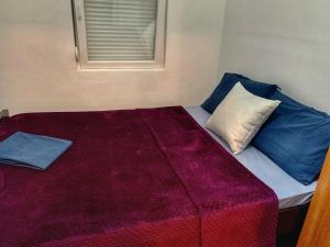 a bed with blue and white pillows and a window at Sanja apartment in Prčanj