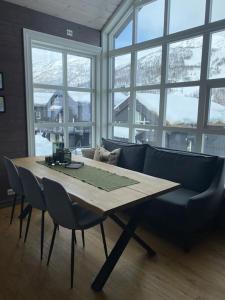 una mesa con sillas y un sofá en una habitación con ventanas en Hytteleilighet på Strandafjellet, en Stranda