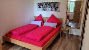 Bett mit roter Bettwäsche und Kissen in einem Zimmer in der Unterkunft Ferienbungalow Sonnenwald Bayerischer Wald in Schöfweg