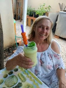 una mujer sentada en una mesa sosteniendo una bebida en Aruba Backpackers, en Oranjestad