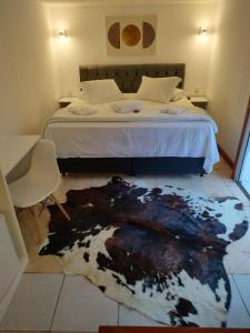 a bedroom with a bed with a cow rug on the floor at Pousada la colline in Santo Antônio do Pinhal