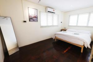 1 Schlafzimmer mit einem Bett mit weißer Bettwäsche und 2 Fenstern in der Unterkunft monstera homestay (Lenggong) in Kampong Ulu Jepai