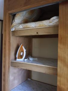 Una litera de madera con un objeto de madera en el estante inferior. en Aruba Backpackers, en Oranjestad