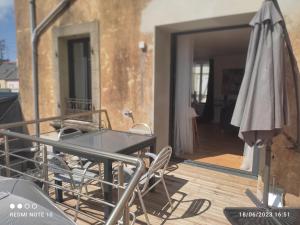 een balkon met een tafel en stoelen en een parasol bij Ty Marok -proche des plage et des commerces in Douarnenez