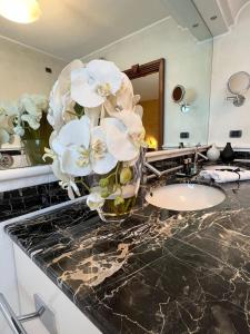 a bathroom counter with a vase of flowers on it at Airport BEA Rooms in Azzano San Paolo