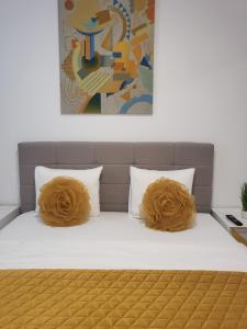 a bed with brown pillows on it with a painting at Hils Pallady Apartment Lyly in Bucharest