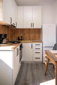 a kitchen with white cabinets and a wooden table at Nina House in Târgu Jiu