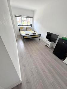 ein Wohnzimmer mit einem Sofa und einem Flachbild-TV in der Unterkunft New Florence Rooms in Mitcham