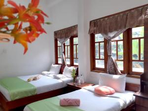 two beds sitting in a room with windows at Subash Hotel in Nallathanniya
