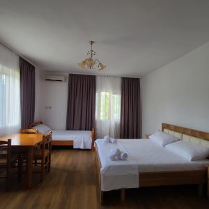 sypialnia z 2 łóżkami i stołem oraz jadalnia w obiekcie Wild River Guesthouse w mieście Përmet