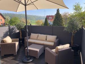 eine Terrasse mit einem Sofa, Stühlen und einem Sonnenschirm in der Unterkunft Ferienwohnung-Meiser in Oberwaroldern