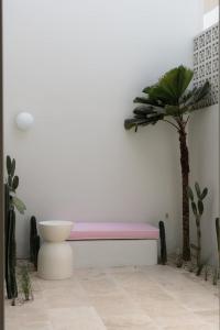 a pink bench against a white wall with a palm tree at The Cali Villas Canggu in Canggu
