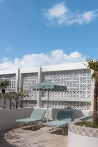 - deux chaises et un parasol sur une terrasse avec un bâtiment dans l'établissement The Cali Villas Canggu, à Canggu