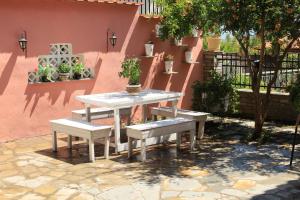 una mesa de picnic y bancos frente a una pared rosa en Η Ροδιά - Rodia en Agios Nikolaos