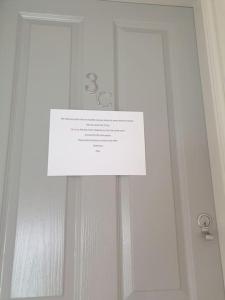 um sinal branco numa porta com uma janela em large comfortable 1st floor apartment with private yard em Longtown
