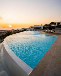 ミコノス・シティにあるAlia Luxury Villa Mykonosの夕日を背景に広いスイミングプール