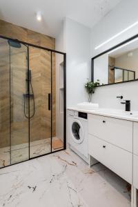 a bathroom with a shower and a sink and a washing machine at Apartament Tower Premium - siłownia, sauna, ścisłe centrum - by Kairos Apartments in Katowice