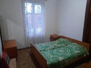 um quarto com uma cama com um edredão verde e uma janela em individual low-budget guest-house em Tsqaltubo