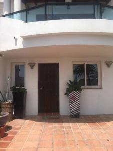 Casa blanca con puerta y ventanas negras en Palm Beach Apartment in La Duquesa, en Manilva