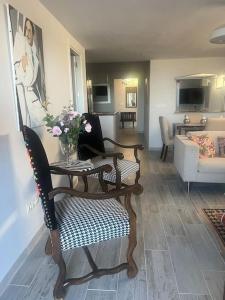 una sala de estar con una silla y una mesa con flores en Palm Beach Apartment in La Duquesa, en Manilva