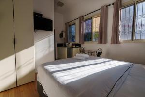 1 dormitorio con 1 cama blanca grande y ventanas en Zimmer Garden en Haifa