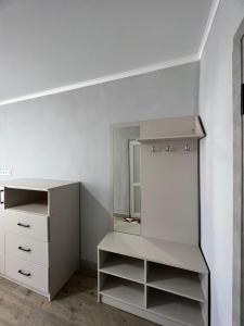 ein weißes Zimmer mit einer Kommode und einem Spiegel in der Unterkunft Гостевой дом Razamlux in Bosteri