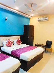 una habitación de hotel con 2 camas y una silla en Hotel Golden Galaxy - Santacruz East, en Bombay