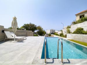 a swimming pool with a chair and an umbrella at Sunset Park Villas in Paphos City