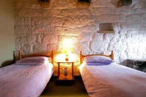 two beds in a room with a stone wall at The Tower at Plane Castle in Stirling