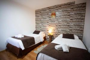 two beds in a room with a brick wall at Tel Hauke Hostal in Punta Arenas