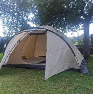 une tente assise dans l'herbe sous un arbre dans l'établissement La Billardière Camping à la Ferme, à Le Ménil-Ciboult