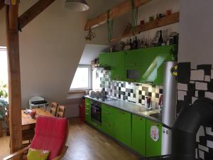 a kitchen with green cabinets and a red chair at Double storey loft in family vila near Prague city center in Prague