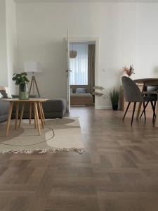 a living room with wooden floors and a table and chairs at Modern új lakás a belvárosban in Debrecen