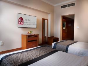 um quarto de hotel com duas camas e uma placa na parede em Retaj Al Rayyan em Doha
