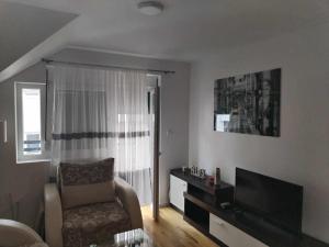 ソコバニャにあるHugo apartmanの椅子とテレビのあるリビングルーム