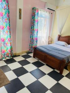 a bedroom with a bed and a checkered floor at Residence Mish in Mahébourg