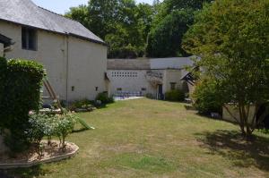 une cour vide à côté d'un bâtiment blanc avec des arbres dans l'établissement Chambre Gargantua Le dolmen, à Thizay