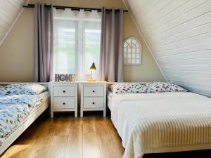 two beds in a attic bedroom with a window at Domki w Tajemniczej Krainie in Wetlina