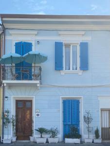 a blue house with blue shutters and a balcony with two umbrellas at Villa Valentina Versilia in Viareggio