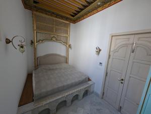 a small bedroom with a bed and a door at Dar Hamouda Guest House - Médina de Tunis in Tunis