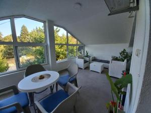 a living room with a table and chairs and windows at Vila Nastovski in Veles